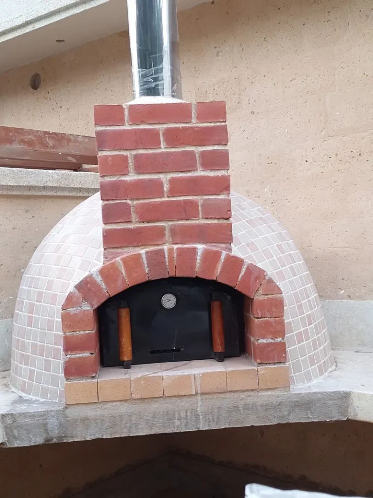 Red brick dome pizza oven with chimney, handcrafted by Kenbrick Ovens