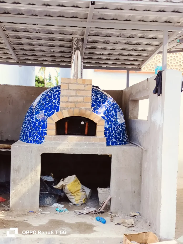 Blue mosaic dome pizza oven under construction at a client site