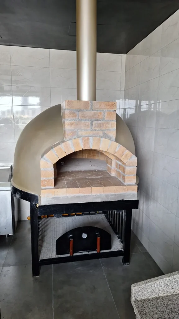 Commercial dome pizza oven with steel flue in a restaurant kitchen